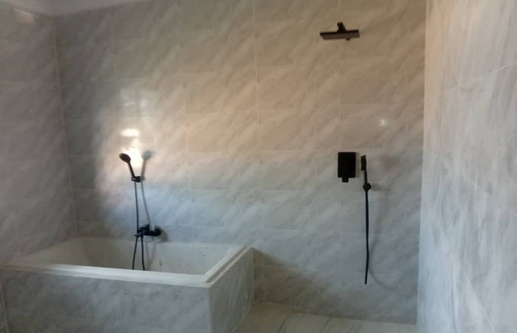 Built-in bath and open walk-in shower with matt black mixers and a linear floor drain
