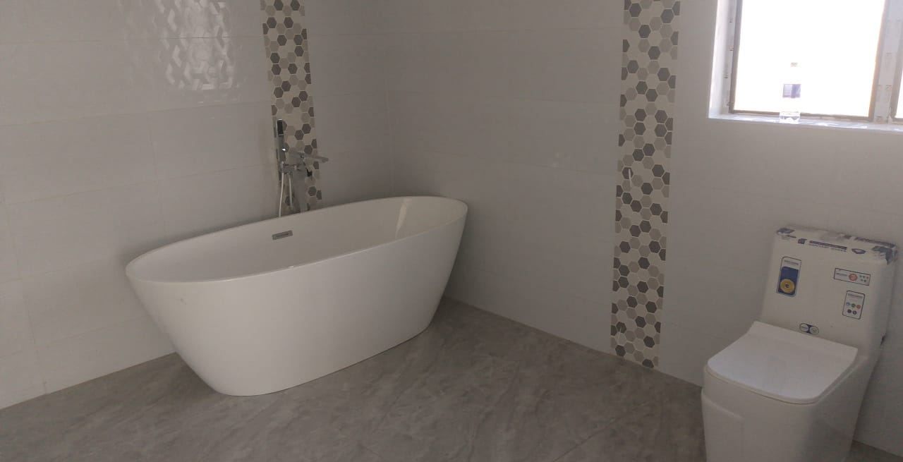Freestanding bath and floor-mounted chrome mixer between hexagonal mosaic feature strips