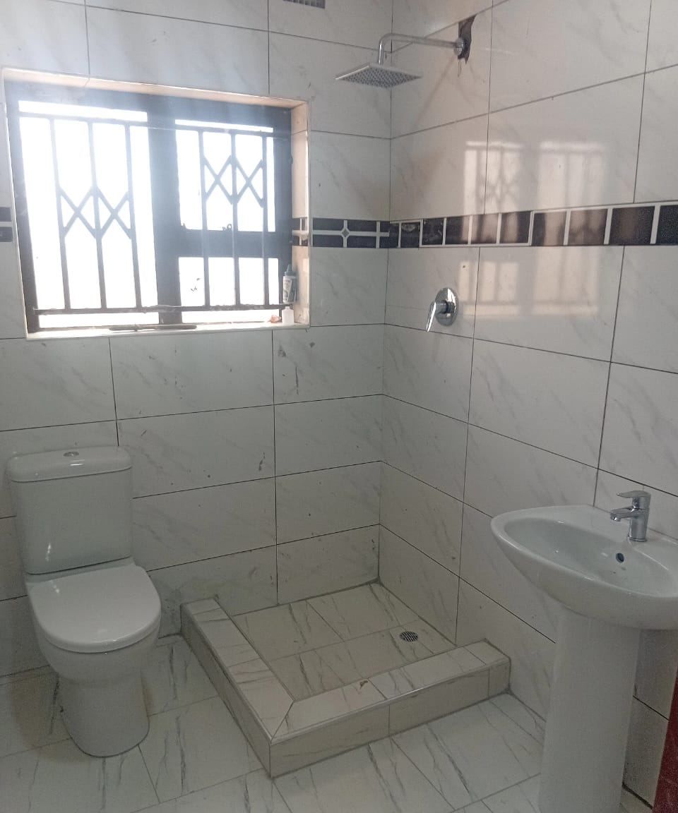 Tiled walk-in shower tray, close-coupled WC and pedestal basin in a marble-effect bathroom